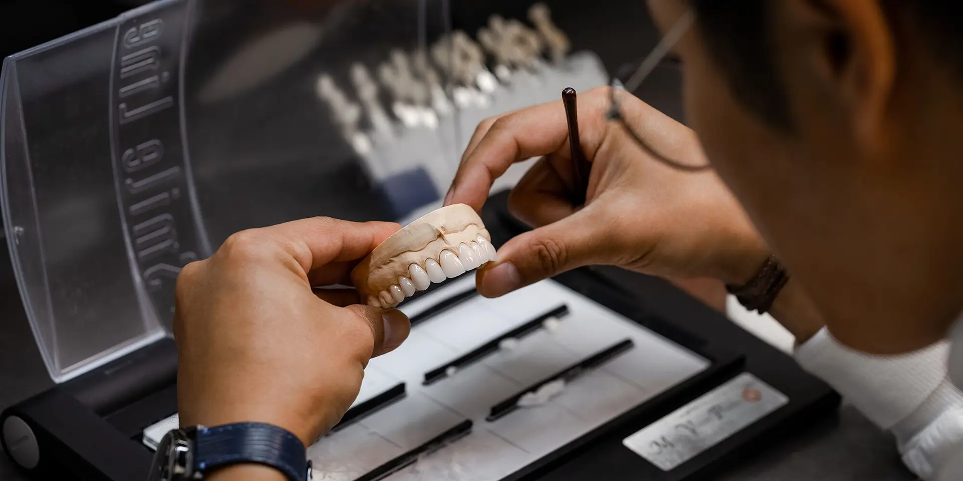 Dental technician working on a prosthetic tooth model in the lab